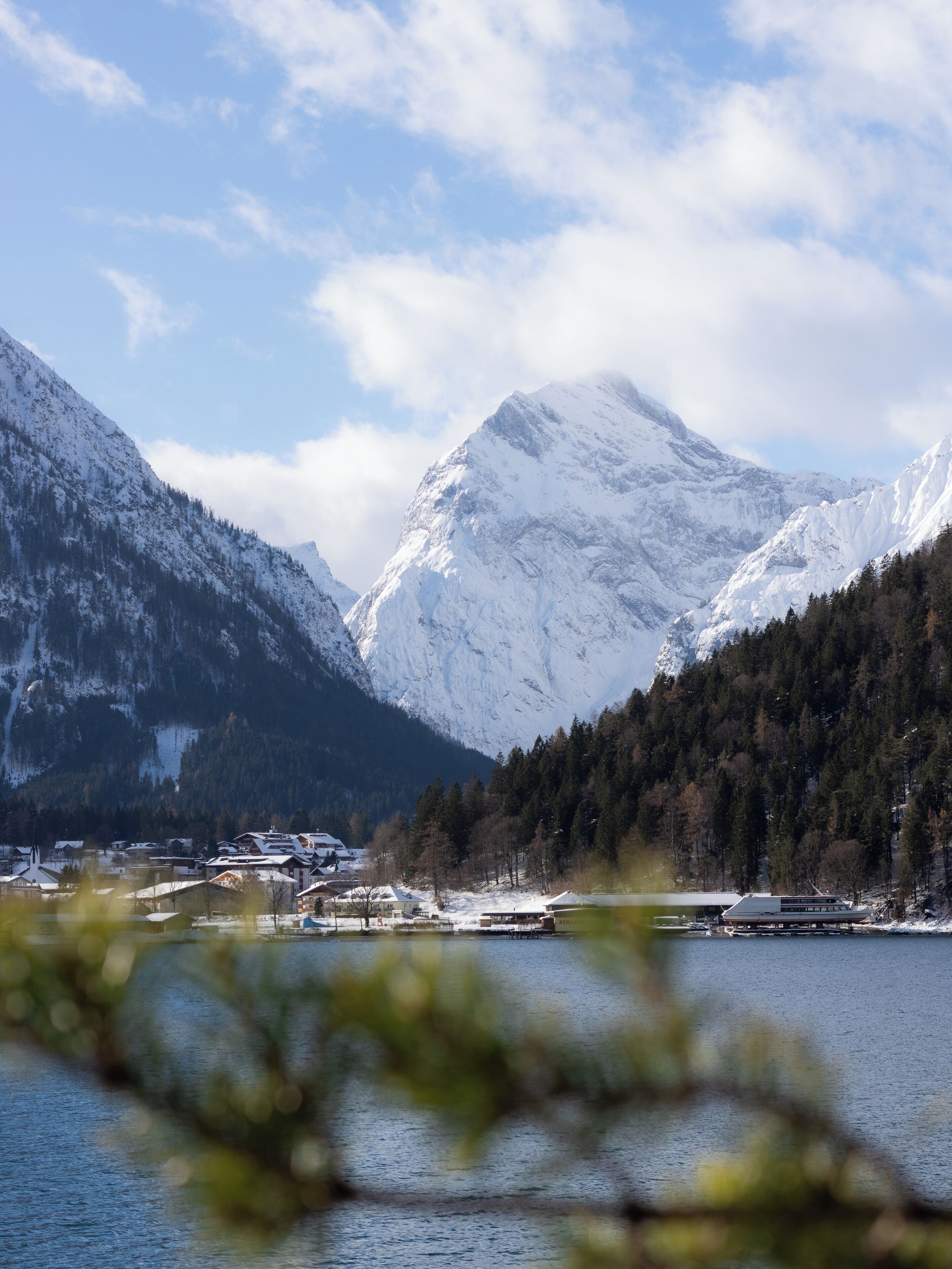 A mountainous landscape with snow-covered peaks and a body of water in the foreground.