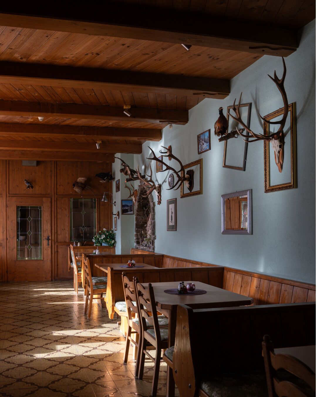 A wooden interior with a high ceiling, wooden benches, and tables.