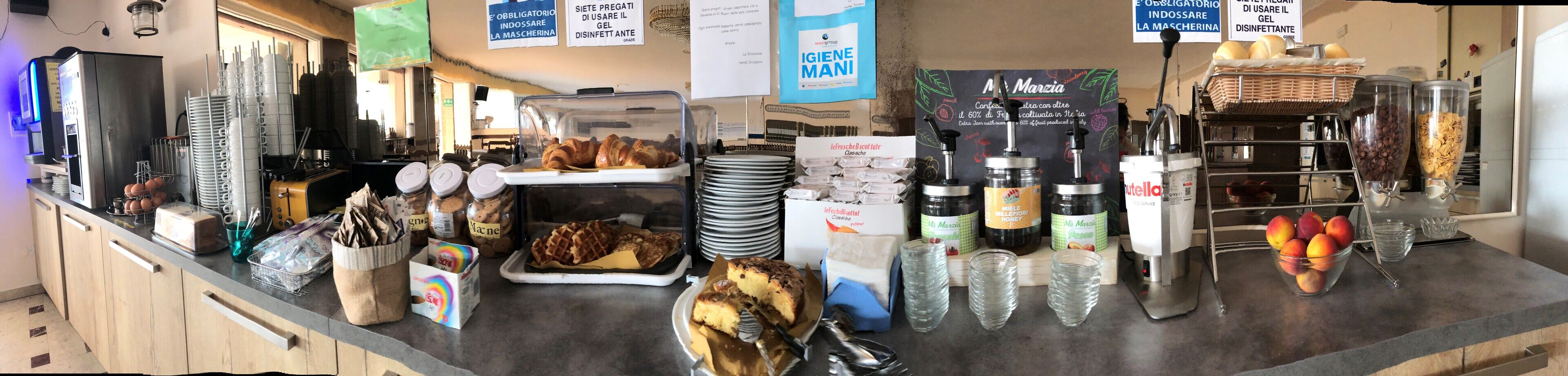 Una vitrina de panadería con diversas opciones de pastelería, frascos de galletas y una exhibición de gofres.