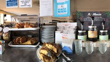 Una vitrina de panadería con diversas opciones de pastelería, frascos de galletas y una exhibición de gofres.
