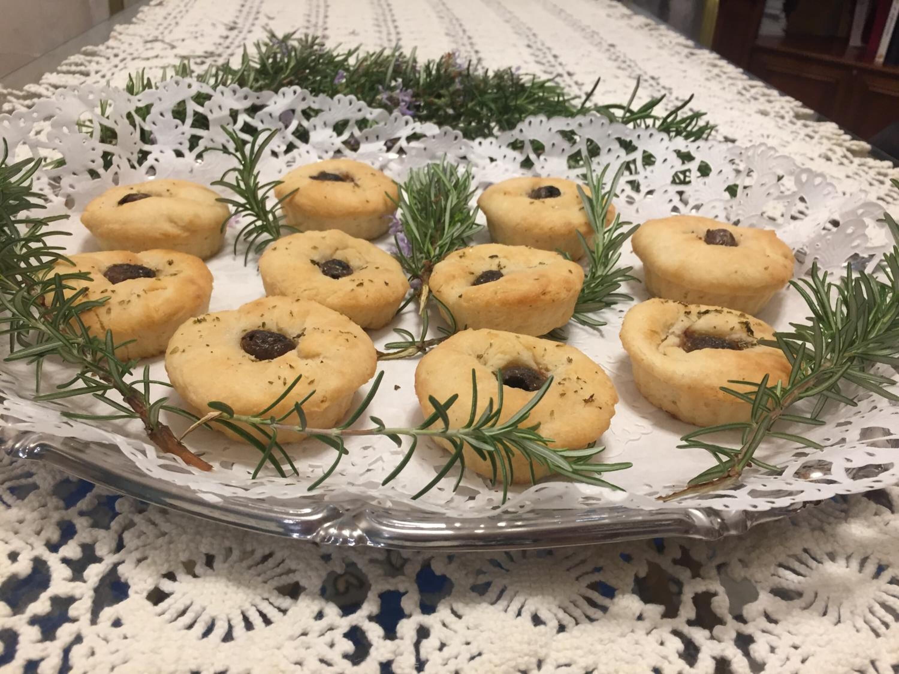 A tray of cookies with rosemary sprigs on a lace tablecloth.