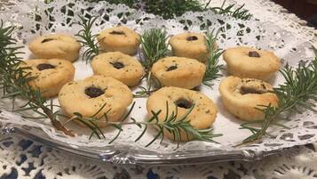 A tray of cookies with rosemary sprigs on a lace tablecloth.