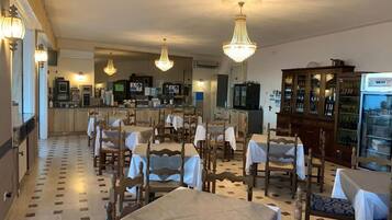 Un restaurante con mesas y sillas de madera, una zona de bar y un candelabro.