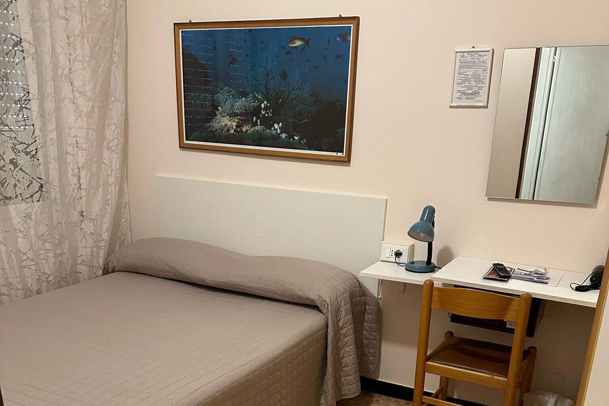 Une chambre à coucher comprenant un lit, un bureau, une chaise, un miroir et un tableau accroché au mur.