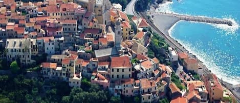 Un pueblo costero con edificios muy juntos, una iglesia destacada con un campanario y una playa a la derecha.