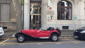 Un descapotable rojo antiguo estacionado frente a un hotel llamado "HOTEL D'ANGLETERRE".