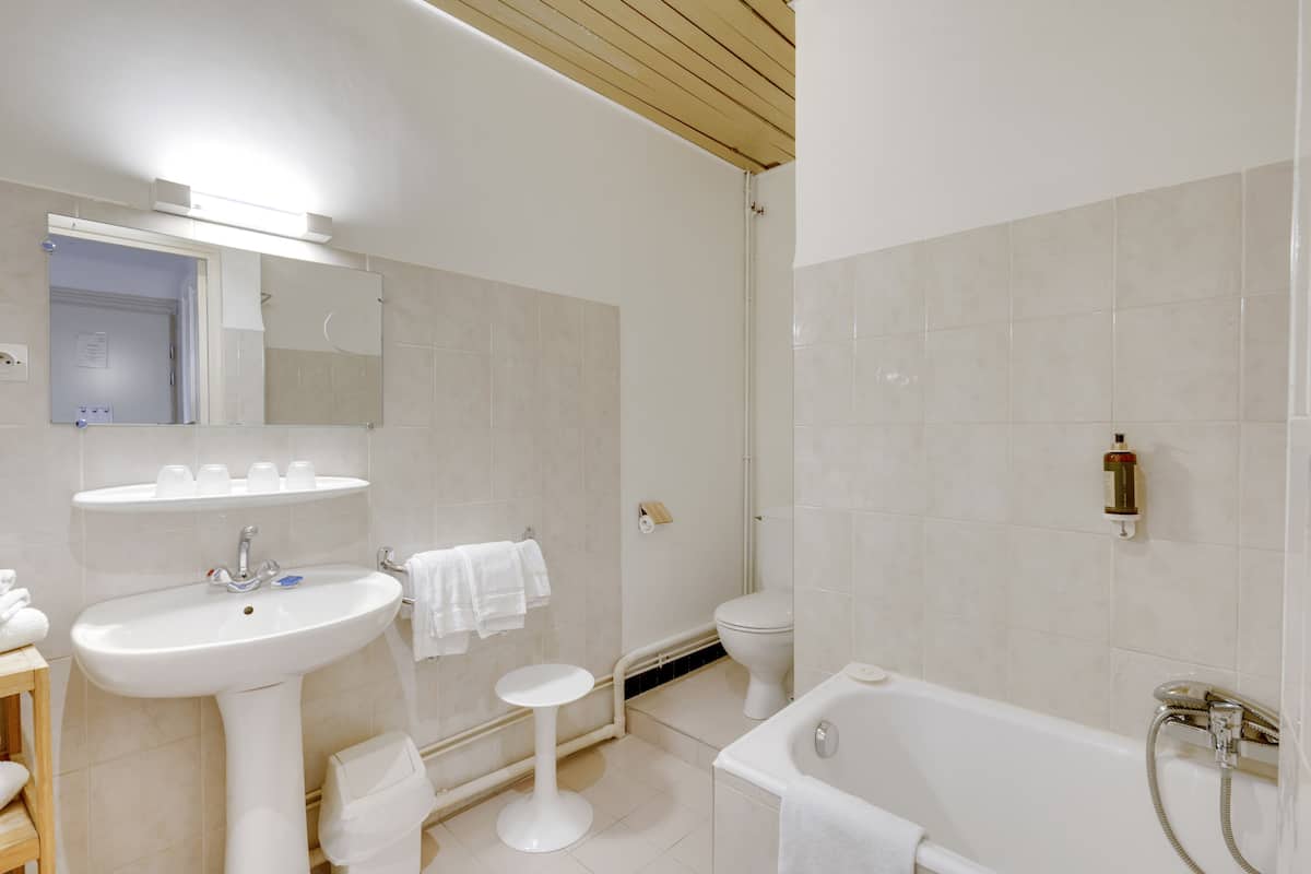 A modern bathroom with a pedestal sink, a toilet, a bathtub, and a mirror.