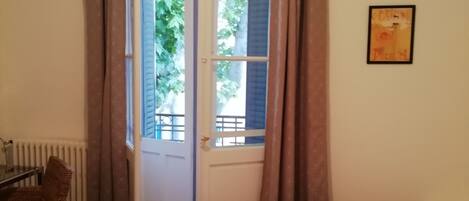 A room with two beds, a chair, a radiator, and a window with curtains.