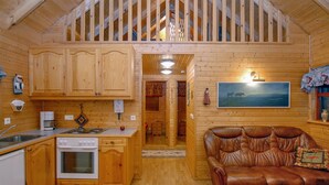 A wooden cabin interior with a kitchen, dining area, and a loft bedroom. - Gljúfurbústaðir (Sveitarfélagid Ölfus)