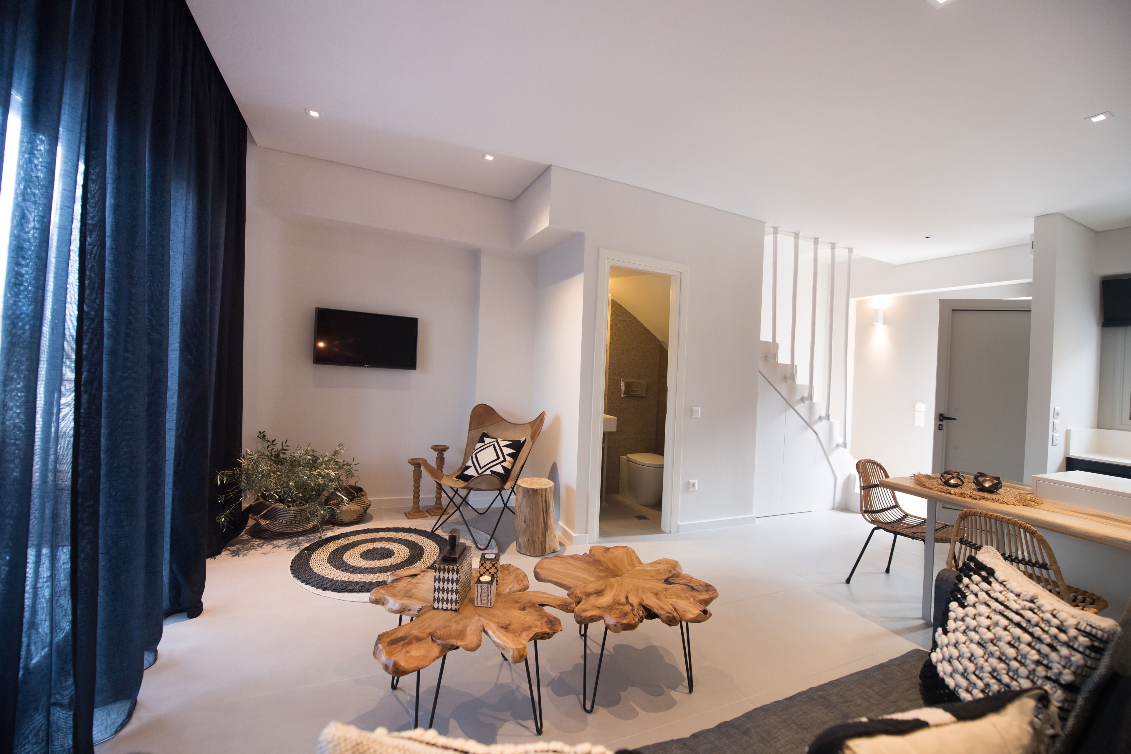 A modern living room with a flat-screen TV, wooden coffee table, and a staircase leading to another level.