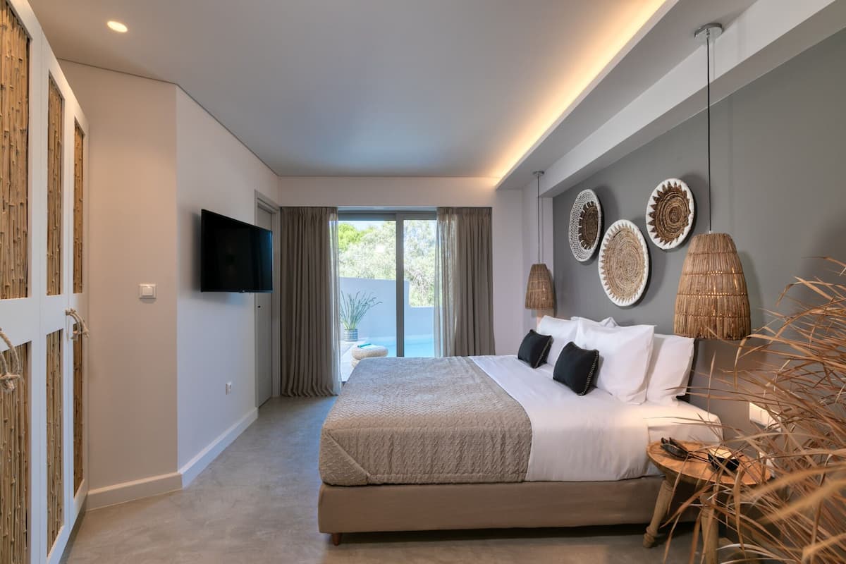 Un dormitorio con una cama grande, un televisor montado en la pared y vistas al exterior a través de una puerta corredera.