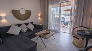 Una sala moderna con un sofá oscuro, una mesa de centro de madera y un sillón de mimbre.