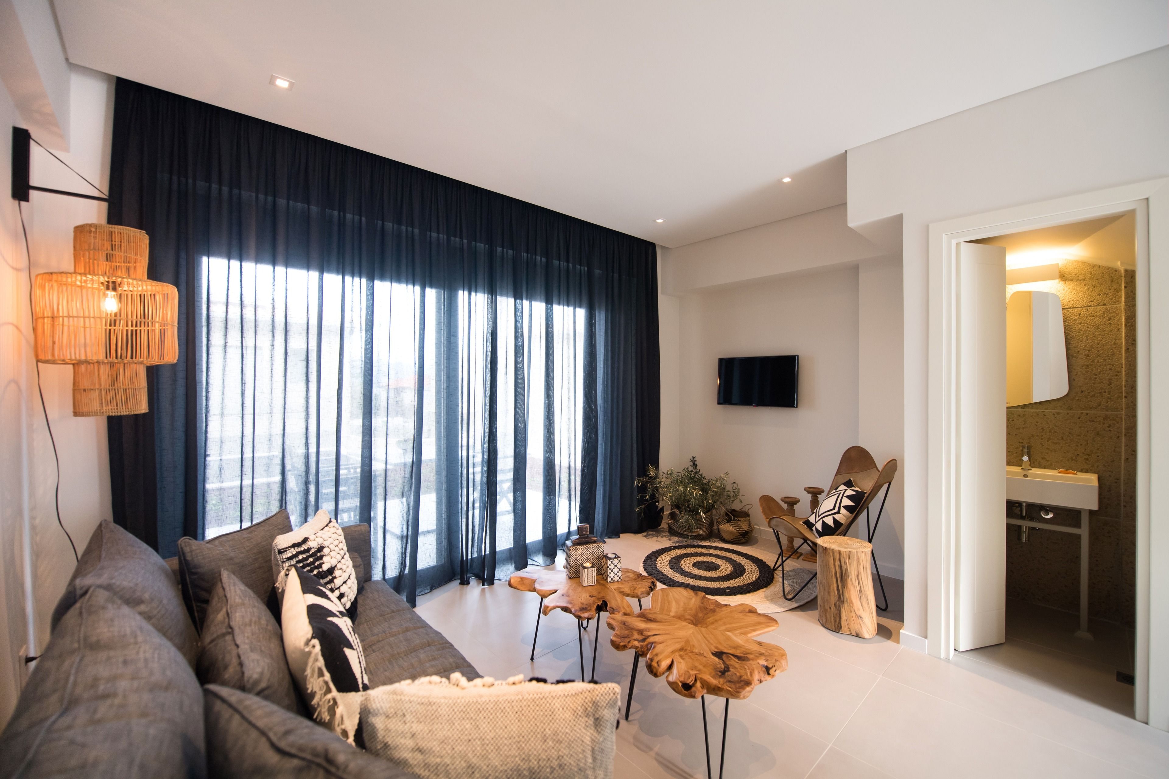 Una sala moderna con sofá, mesa de centro y televisor. Se ve un baño a través de una puerta abierta.