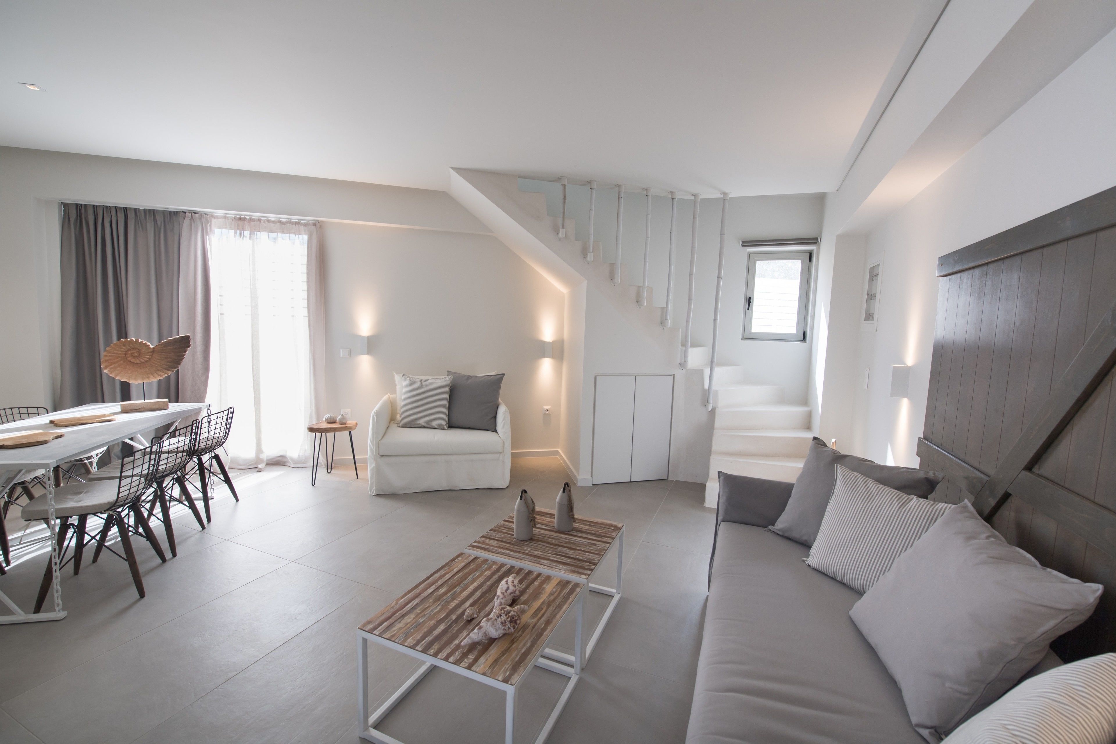 A modern living room with a dining area, a staircase, and a sofa.