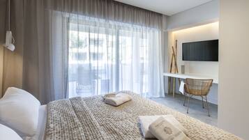 A hotel room with a large bed, a desk with a flat-screen TV, and a chair.