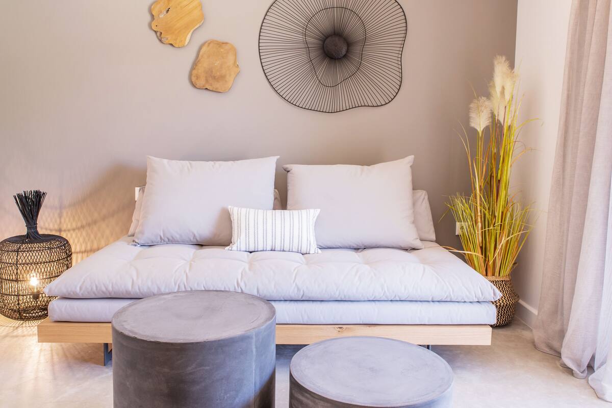 Una sala moderna con un sofá, dos mesitas redondas y decoración en la pared.