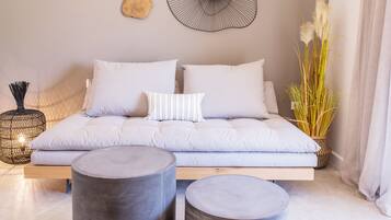 Een moderne woonkamer met een bank, twee ronde bijzettafels en decoratieve wandkunst.