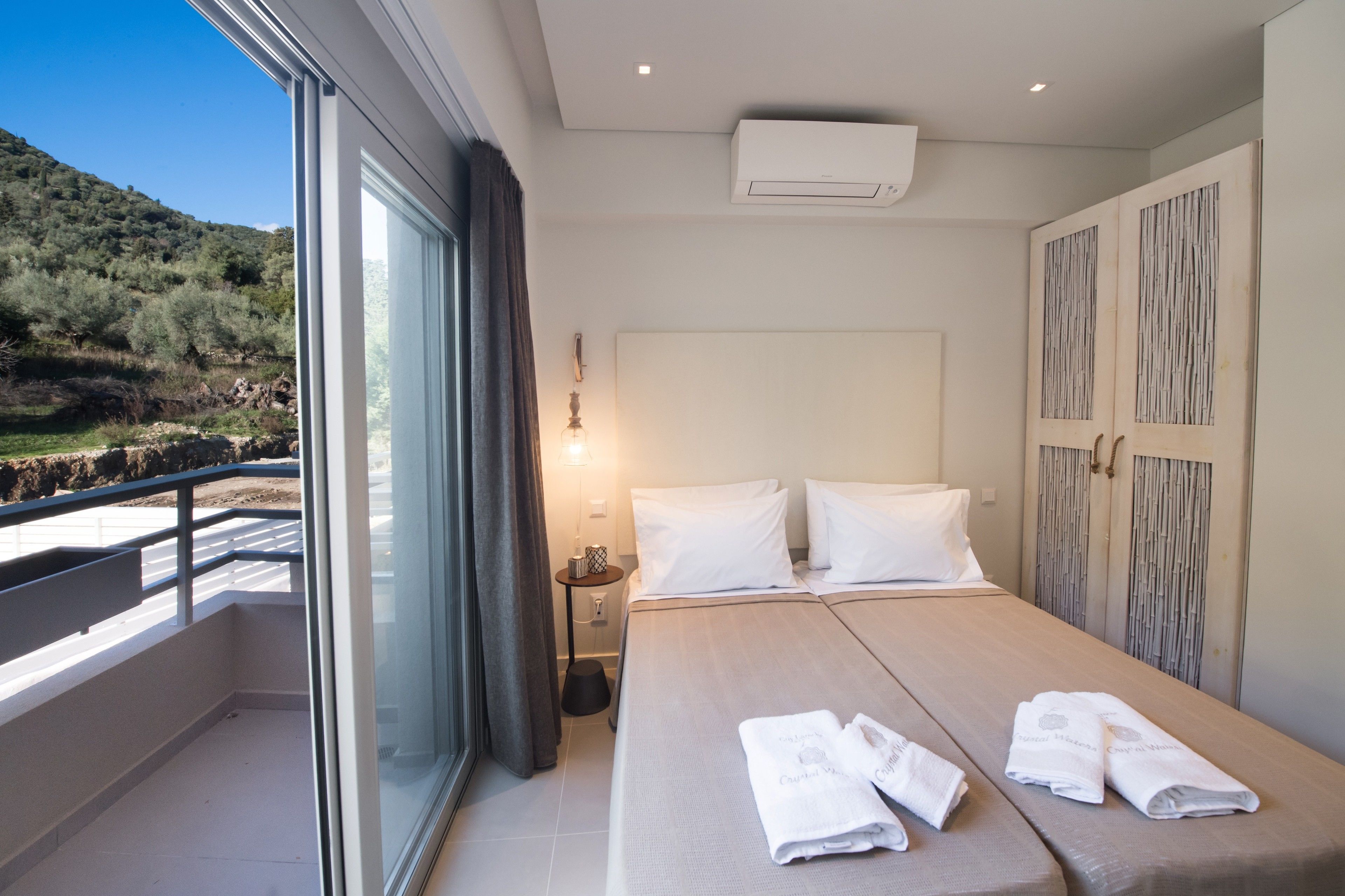 A hotel room with a large bed, a balcony with a view of the countryside, and a modern design.