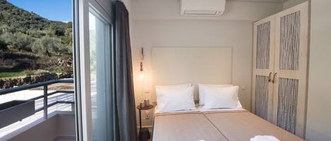 Habitación de hotel con una cama grande, un balcón con vistas al campo y un diseño moderno.