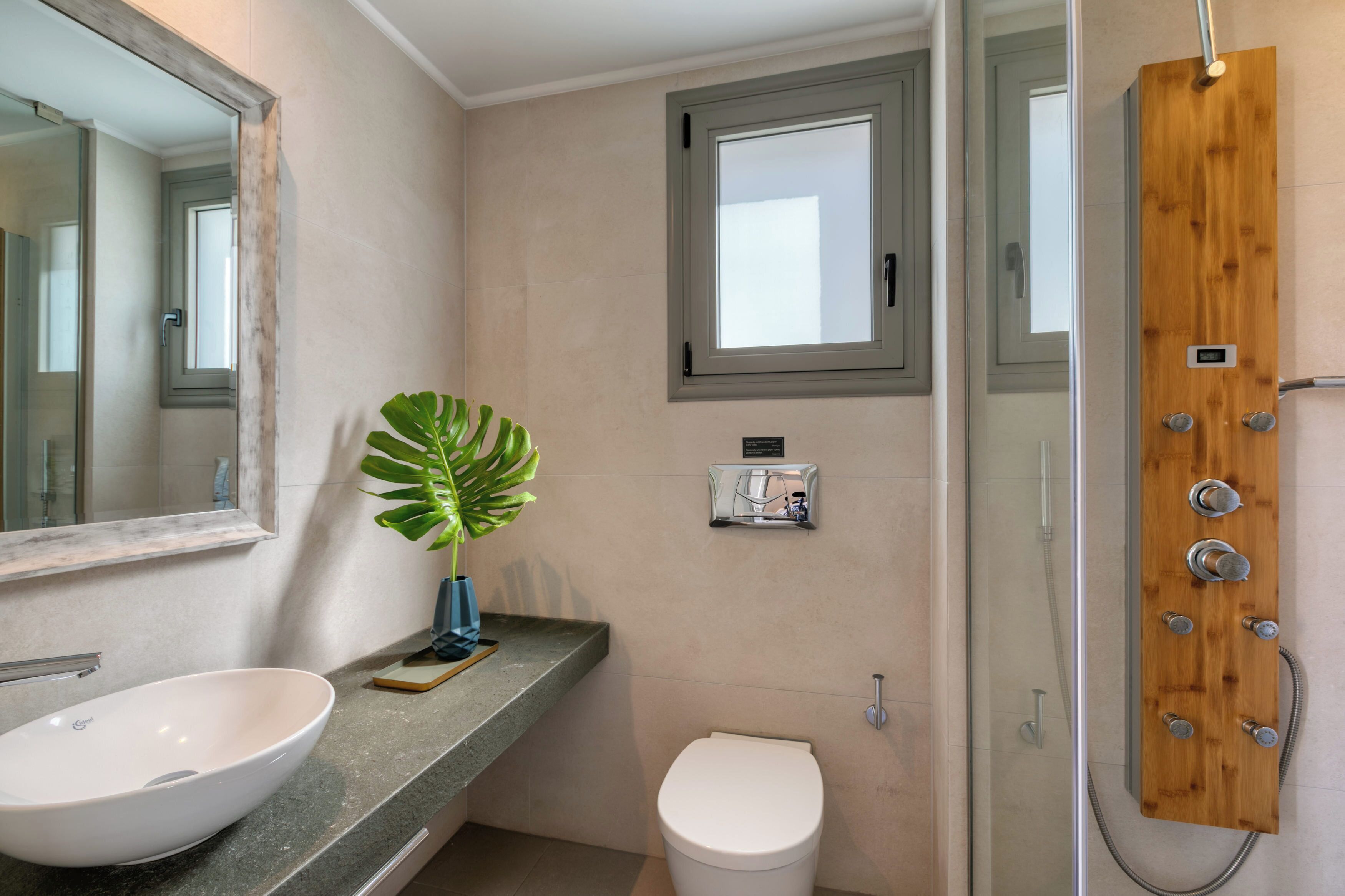 A bathroom with a large mirror, a white sink, a toilet, and a shower enclosure.