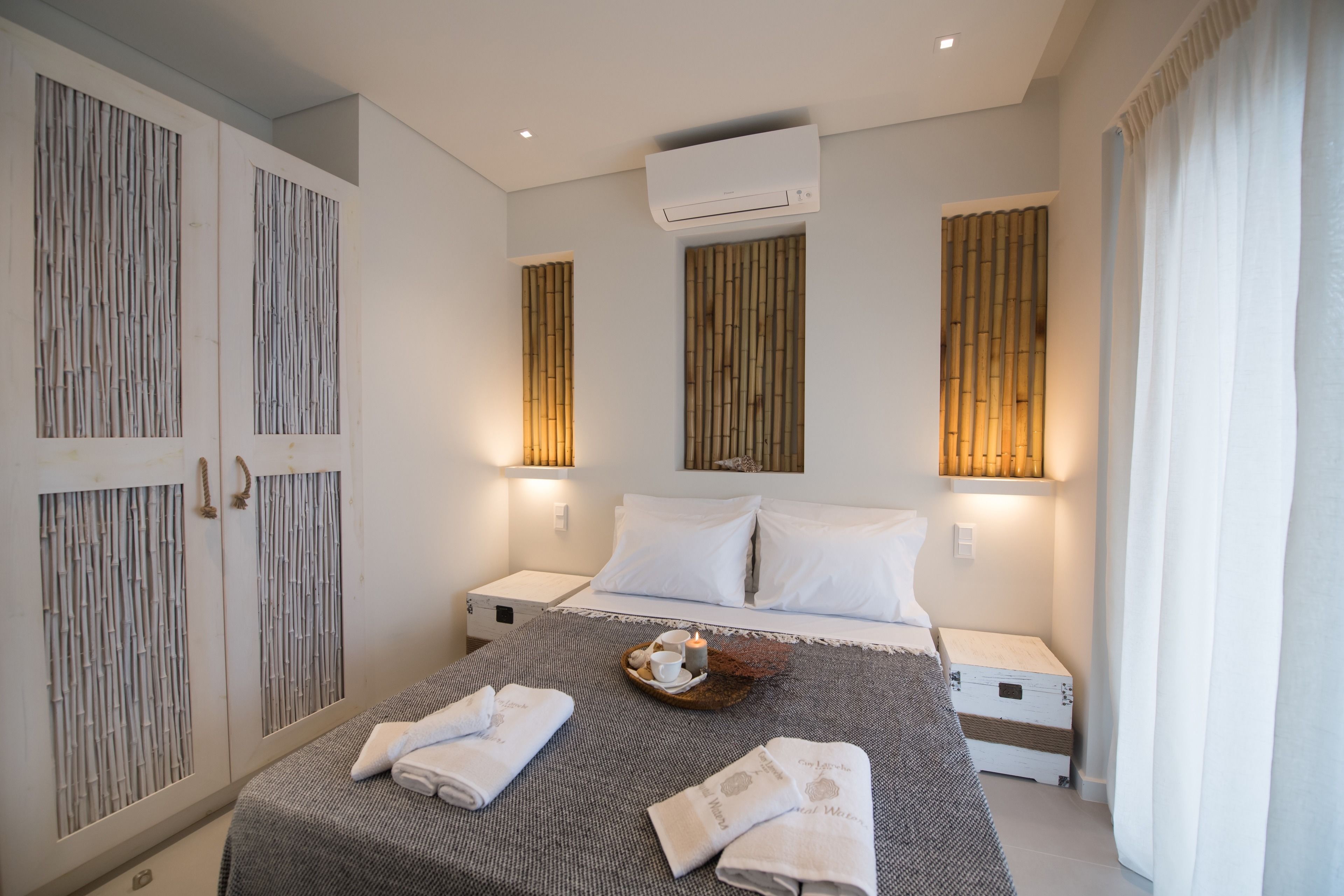 A modern hotel room with a large bed, two bedside tables, a wardrobe, and wall-mounted lighting.