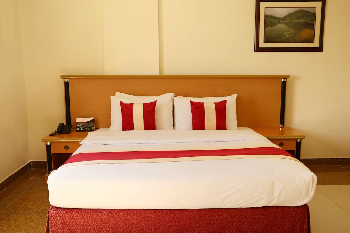 A hotel room with a large bed, two bedside tables, a nightstand, and a framed picture on the wall.