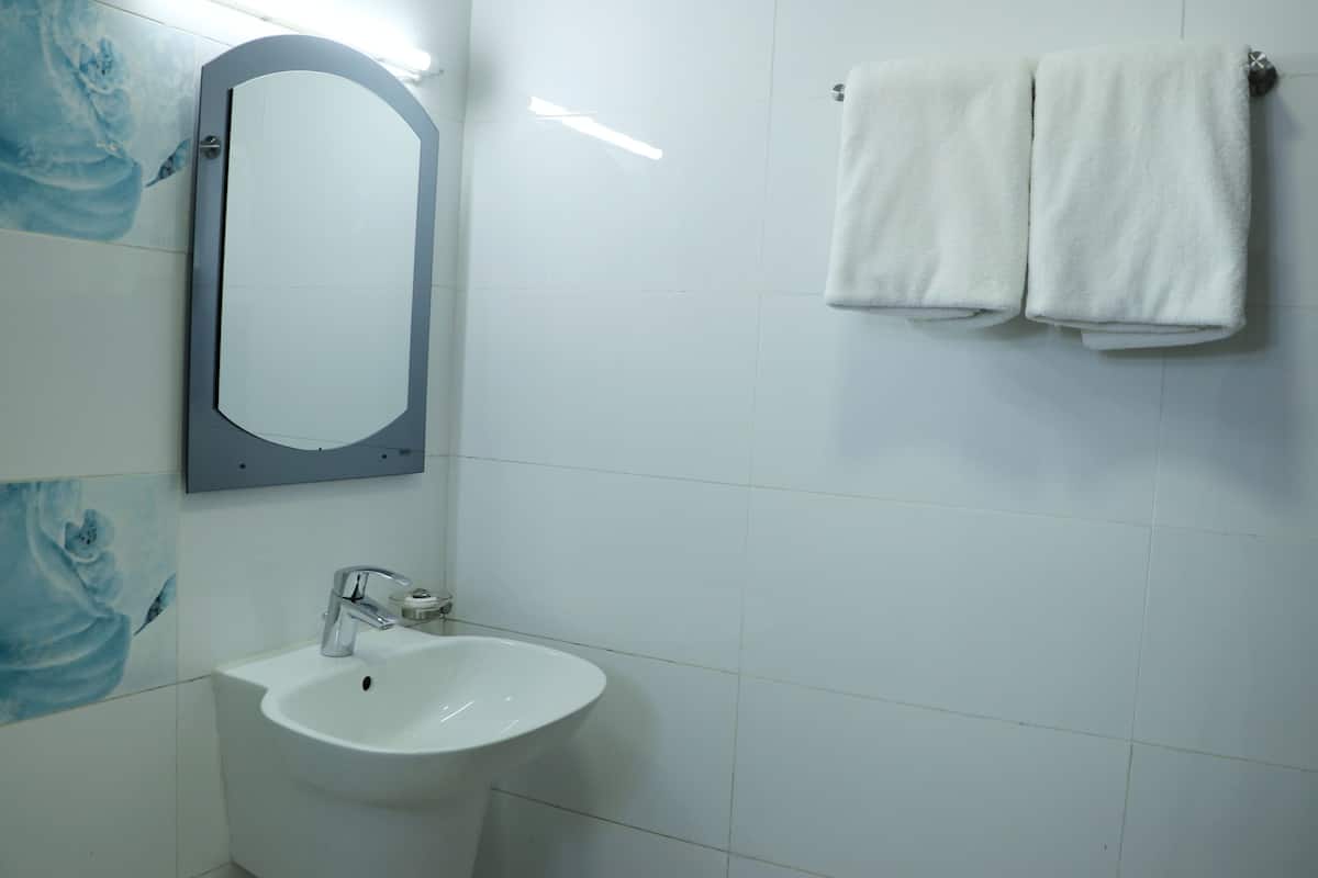 A bathroom with a white sink, a mirror, and two towels hanging on a rack.