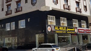 Un edificio de varios pisos con un letrero que dice 'Al-Nile Furnished Flats'.