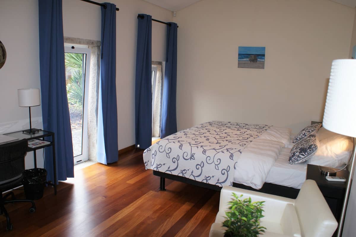 Une chambre à coucher avec un lit, un bureau, une chaise, une lampe et une fenêtre avec des rideaux.