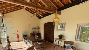 A spacious patio area with wicker furniture, a dining table, and a ceiling fan. - Casa Aguas Mansas (Cantanhede)