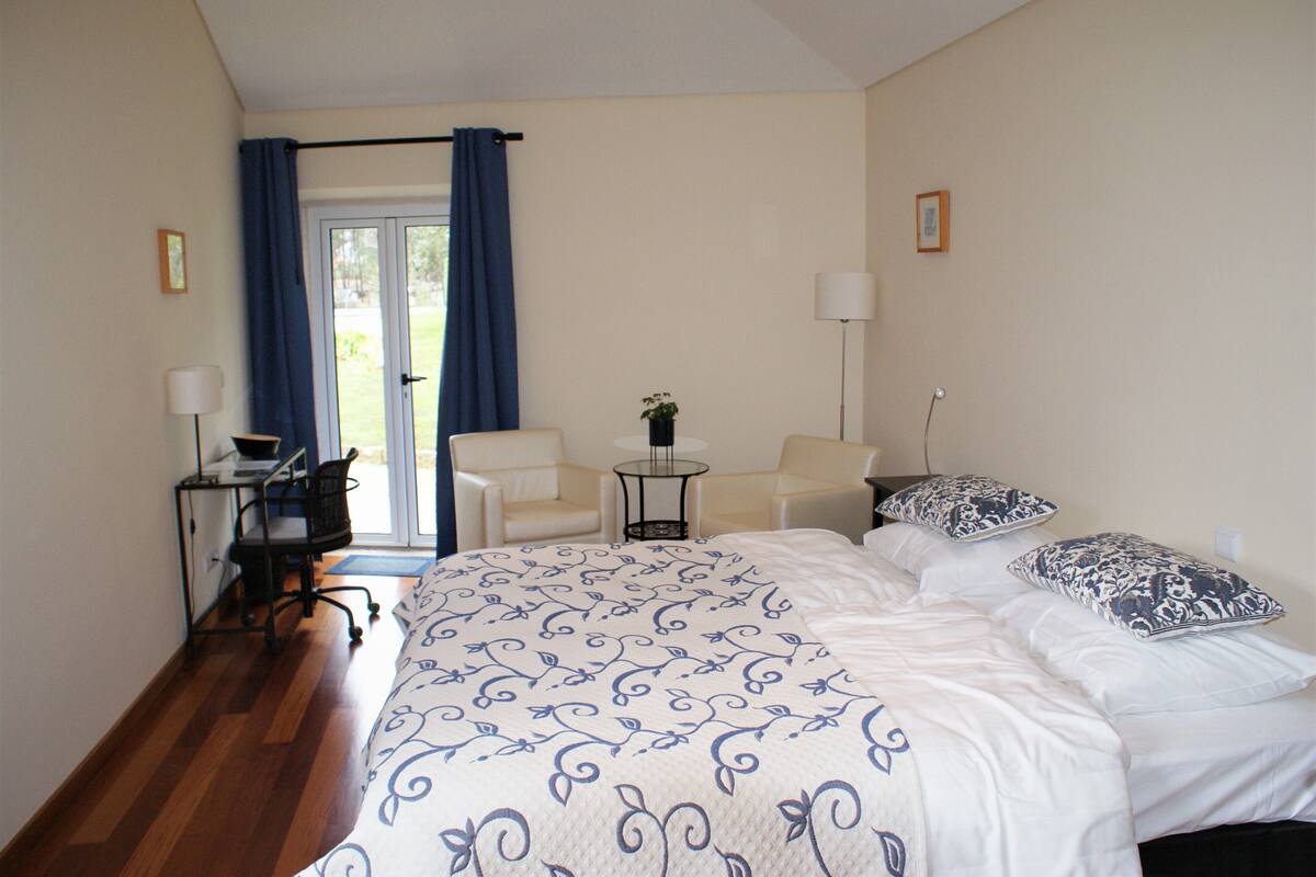 Une chambre d’hôtel avec un grand lit, deux chaises, un bureau et une petite table.