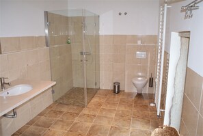 Un baño con ducha de vidrio, lavamanos e inodoro.