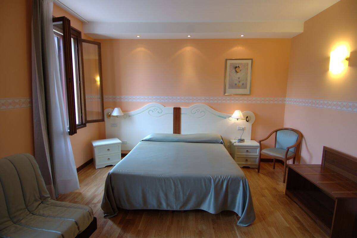 A bedroom with a large bed, bedside tables, a chair, and a desk.