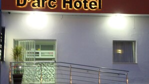 The exterior of D'arc Hotel with a prominent illuminated sign, a gated entrance, and a small window. - D'arc Hotel (Goiania)