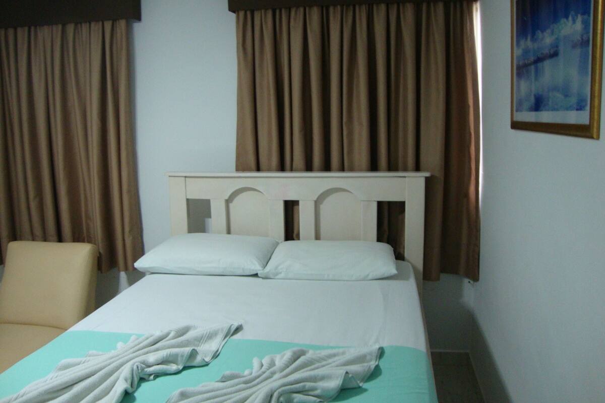 Ein Hotelzimmer mit einem Bett, zwei Kissen, einem Sessel und einem Bild an der Wand.