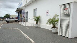 A hotel entrance with a reception desk, potted plants, and a closed metal shutter door. - D'arc Hotel (Goiania)