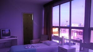 A hotel room with two beds, a TV, and a view of the city through large windows. - D'arc Hotel (Goiania)