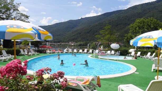 Une piscine avec plusieurs couloirs de nage, entourée de chaises longues et de parasols.