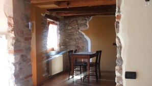 Un coin repas aux murs de pierre, avec une table et des chaises en bois, une cheminée en pierre et un plafond en bois.