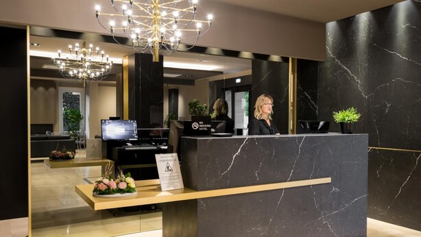 Una recepción de hotel con diseño moderno, una araña y un cartel que indica prohibido fumar.