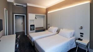 Habitación de hotel con dos camas, un escritorio, una silla, un televisor y un minibar.