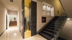 Un interior moderno con una escalera, paredes de mármol e imágenes enmarcadas.