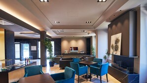 Un moderno vestíbulo de hotel con una recepción, zona de estar y un bar.