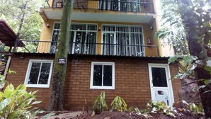 A two-story building with a brick facade, multiple windows, and a balcony. - River edge Bungalow (Rattota)