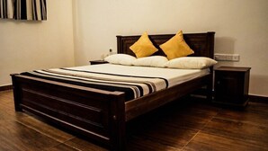 A neatly made bed with a wooden frame and a striped bedspread. - River edge Bungalow (Rattota)