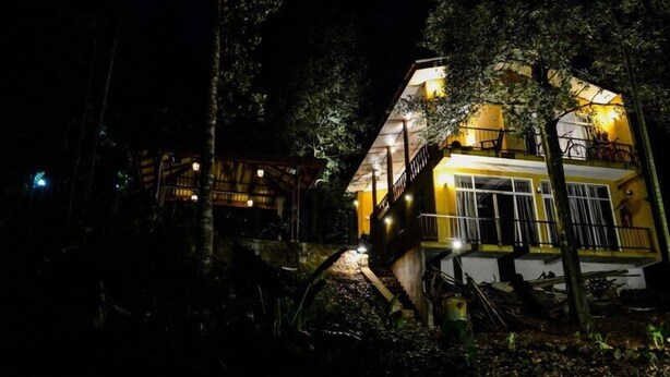 A two-story building with a balcony and a staircase leading to the upper floor. - River edge Bungalow (Rattota)