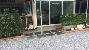Un restaurant doté d’une terrasse couverte, d’une entrée avec porte vitrée et d’un menu écrit à la craie sur un tableau noir.