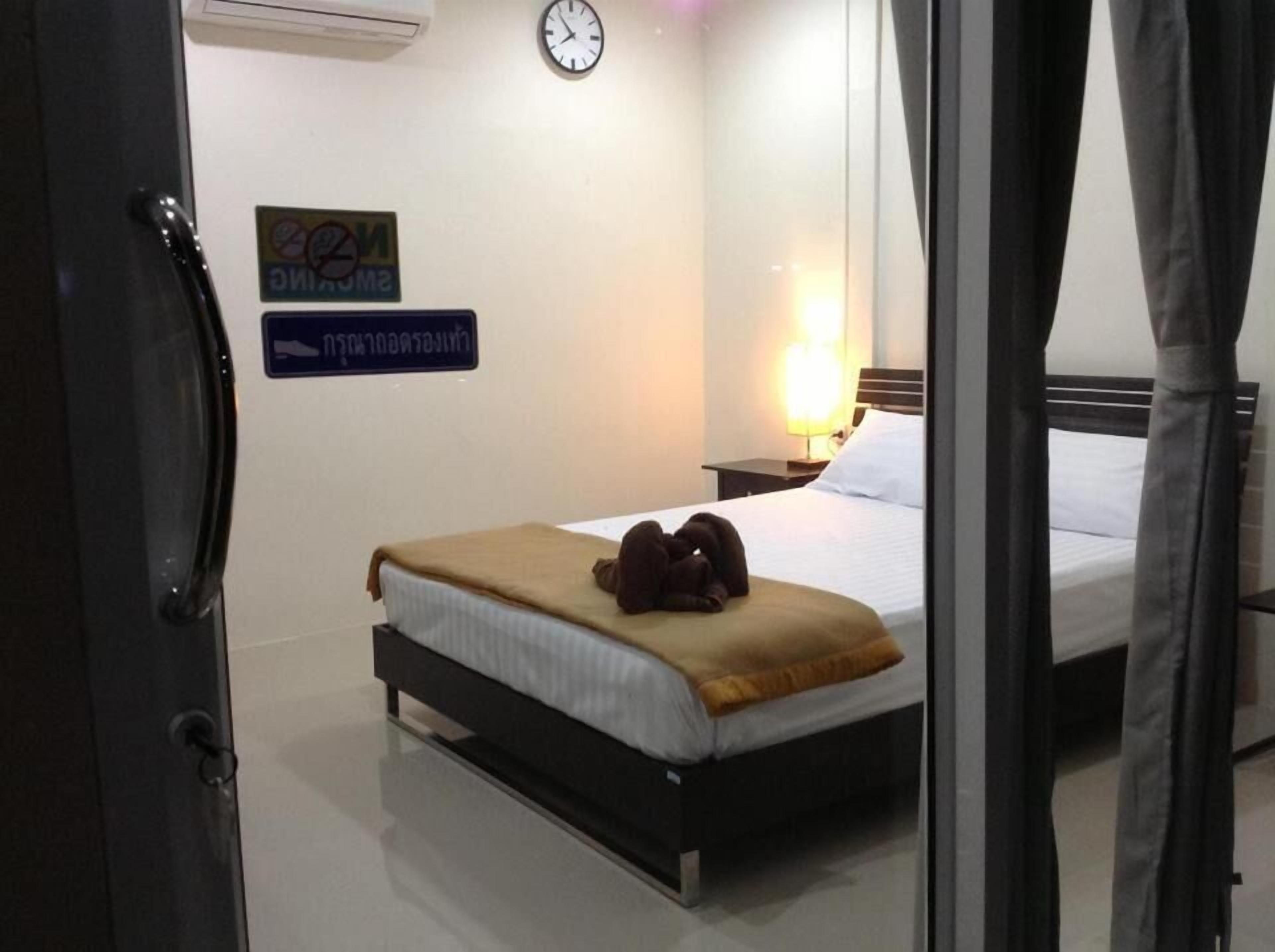 A hotel room with a bed, a clock, and a sign on the wall.