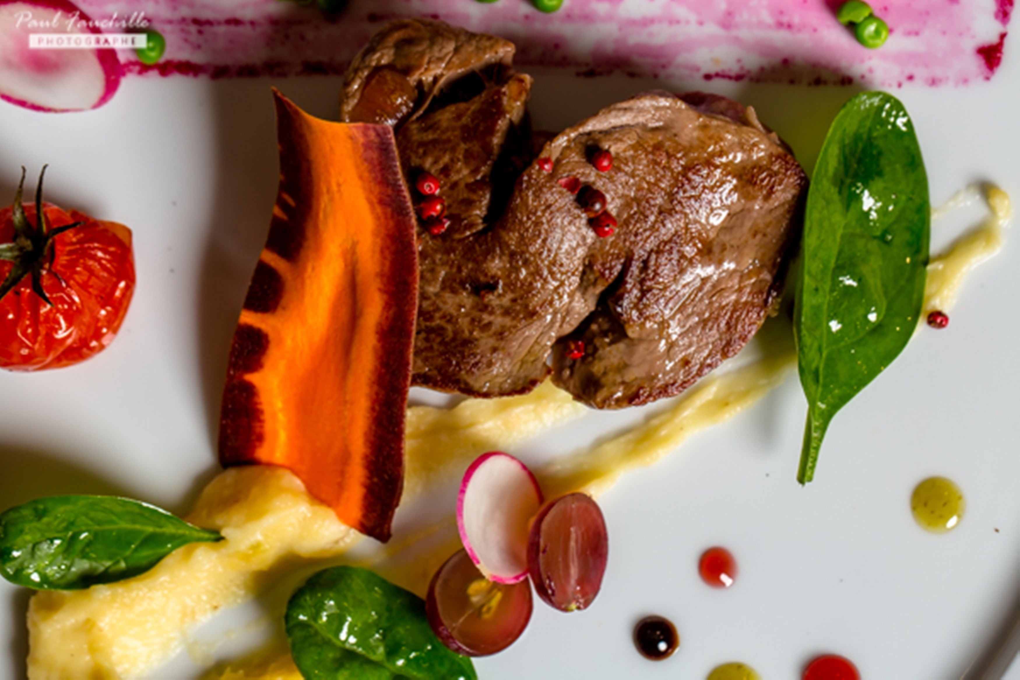 A plate of food with various ingredients including meat, vegetables, and garnishes.