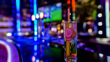 A bar setting with a glass of drink, blurred background lights, and a sign reading "Fanchille PHOTOGRAPHY".